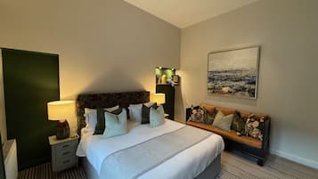 Habitación de hotel con una cama, mesitas de noche, un sofá, un cuadro y una pared verde.