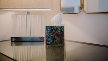 A hotel room with a bedside table, a lamp, a tissue box, and a mirror.