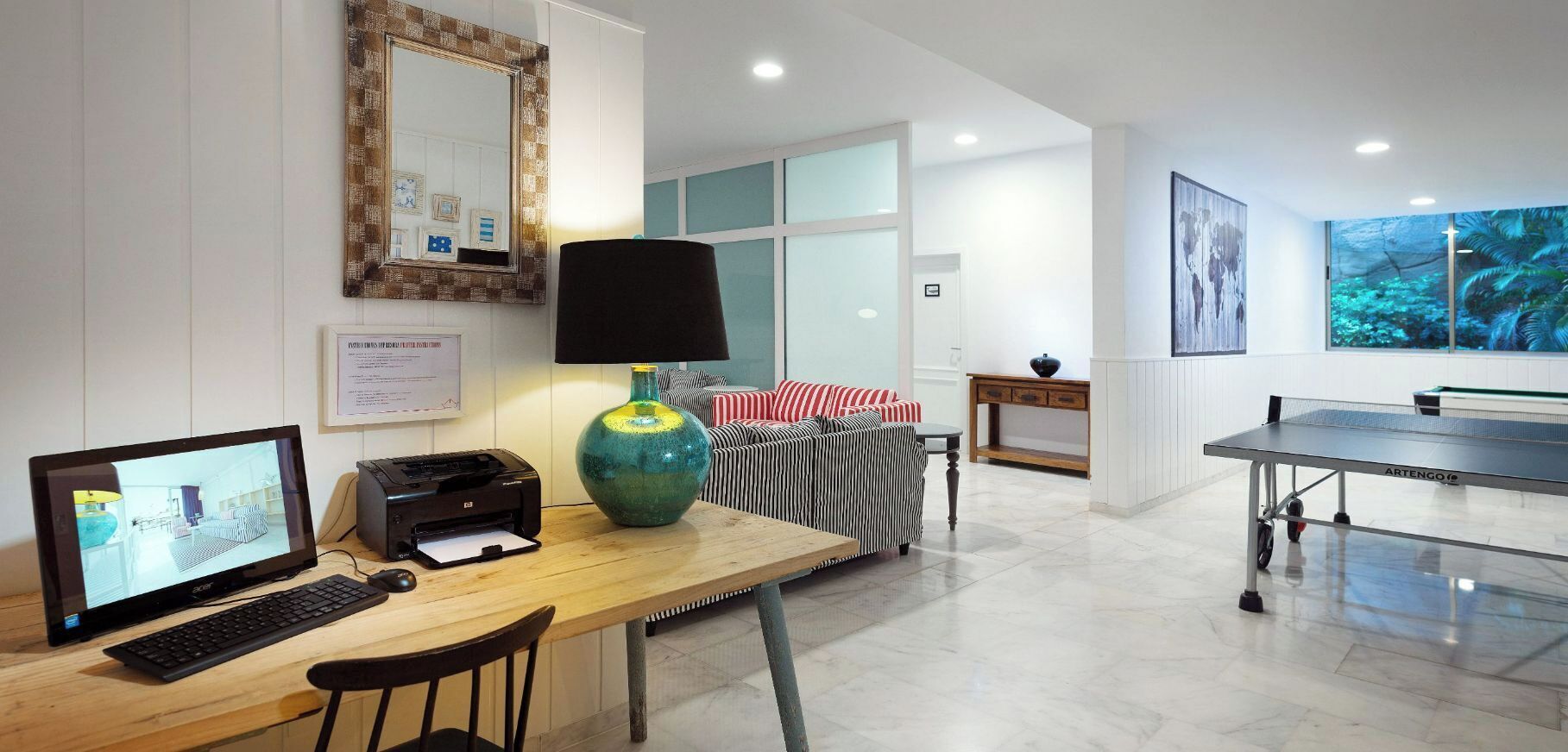A modern living room with a computer, printer, and a ping pong table.