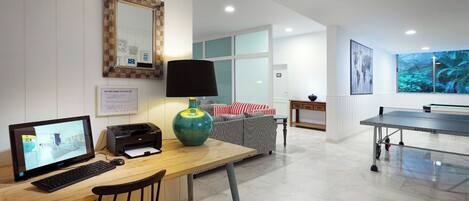 A modern living room with a computer, printer, and a ping pong table.