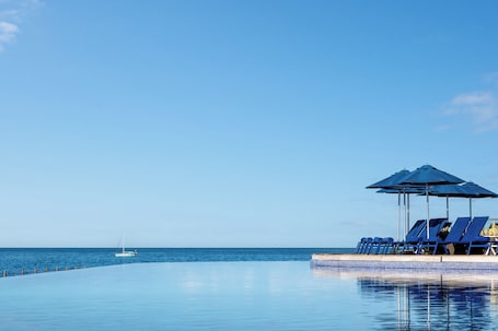 Una piscina al aire libre, sombrillas, sillones reclinables de piscina