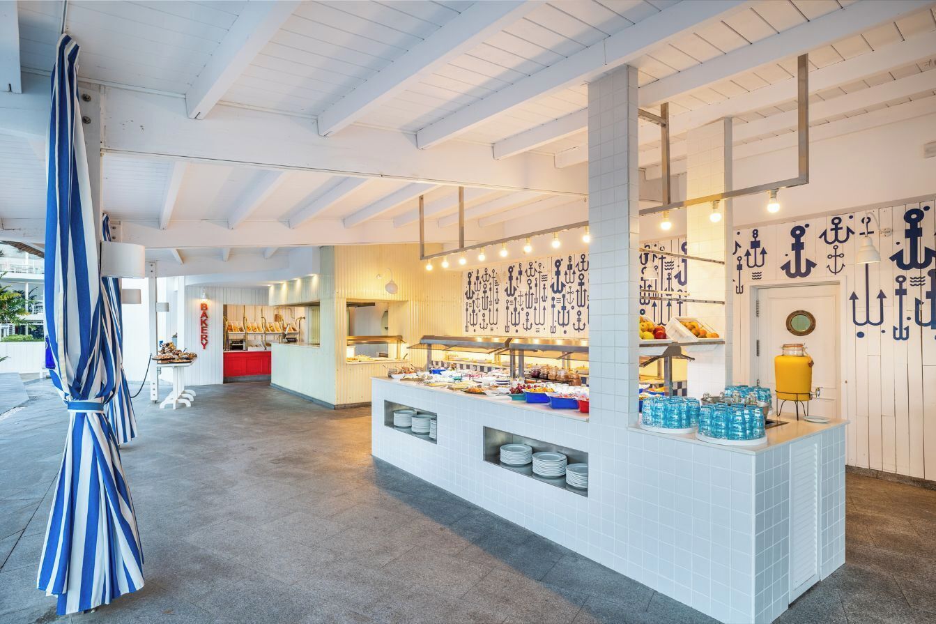 Zona de buffet con mostrador, platos y dispensadores de agua.