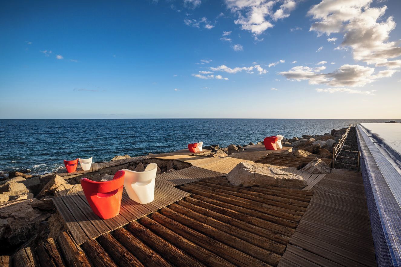 A wooden deck with seating and a view of the sea.
