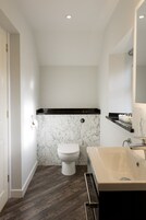 Un baño con inodoro, bañera y pared de mármol.