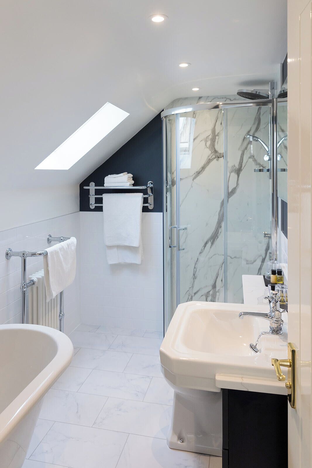 A modern bathroom with a glass shower enclosure, a freestanding bathtub, and a vanity with a sink and mirror.