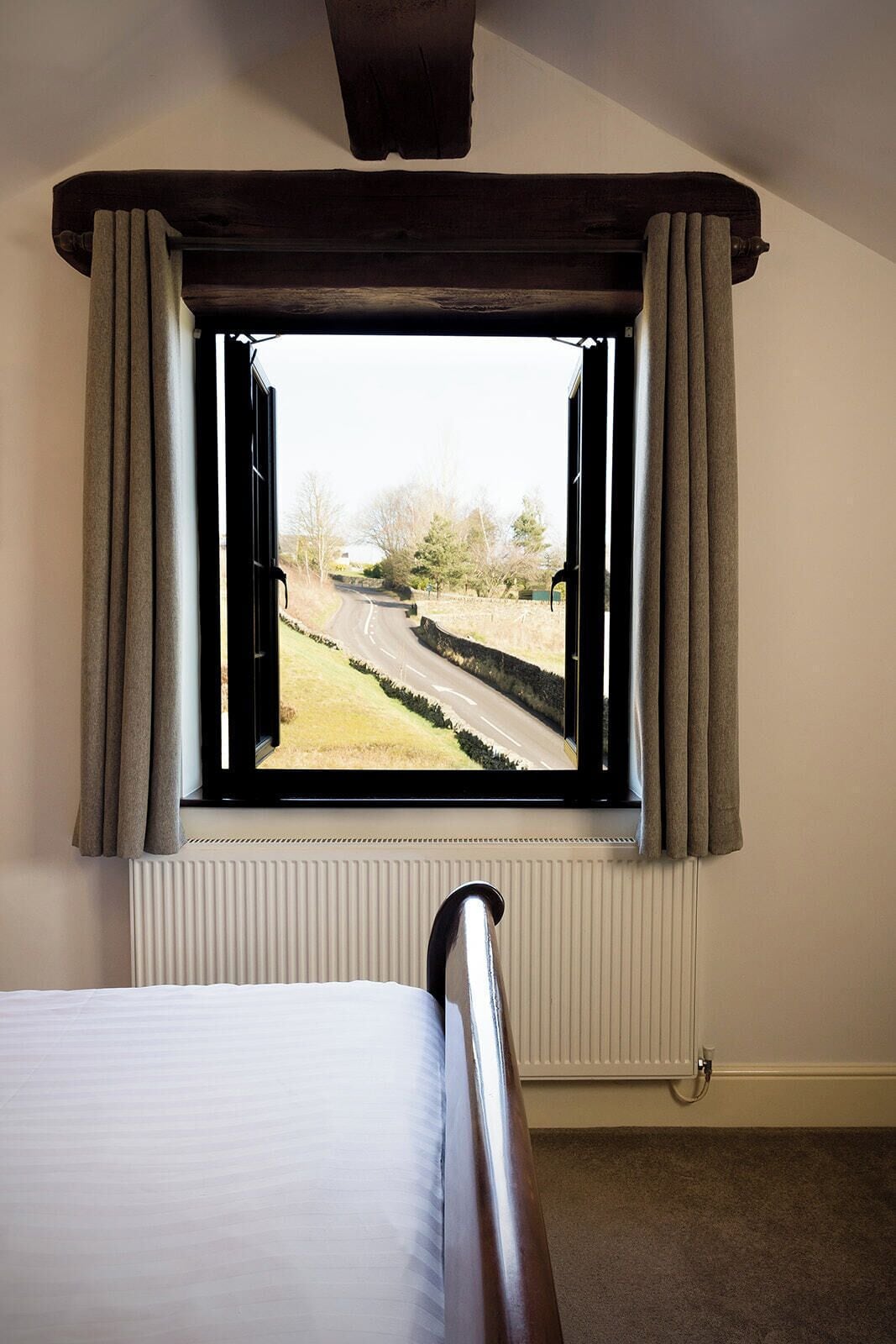 A bedroom with a large window, a bed, and a radiator.