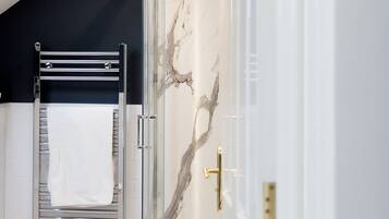 Un baño moderno con cabina de ducha de vidrio, un perchero y una manija visible.
