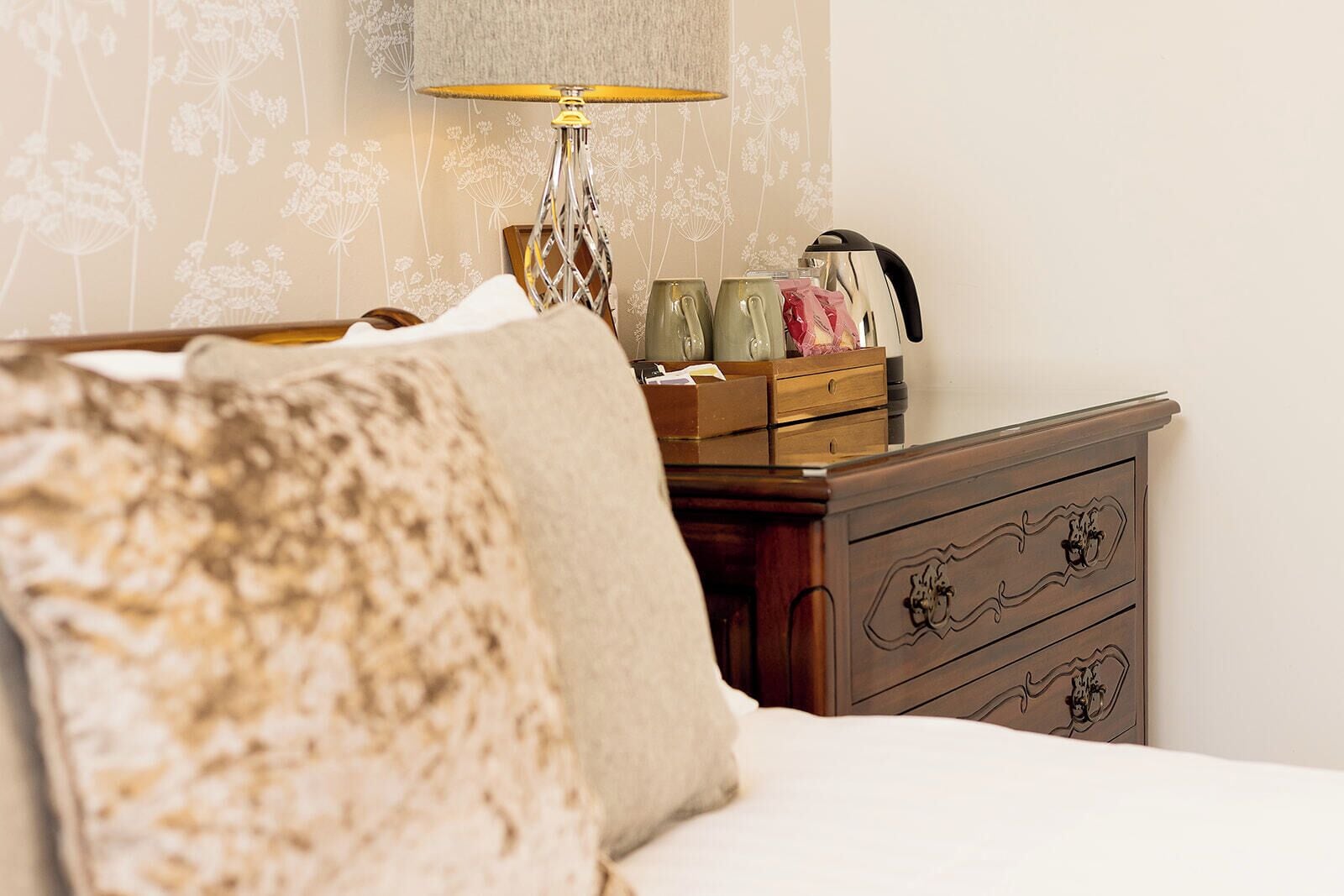 Une chambre à coucher avec un lit, une commode en bois, une lampe et une table de chevet avec une lampe.