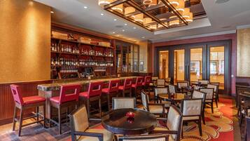 A bar area with multiple seating options, including bar stools and tables, and a well-stocked liquor shelf.