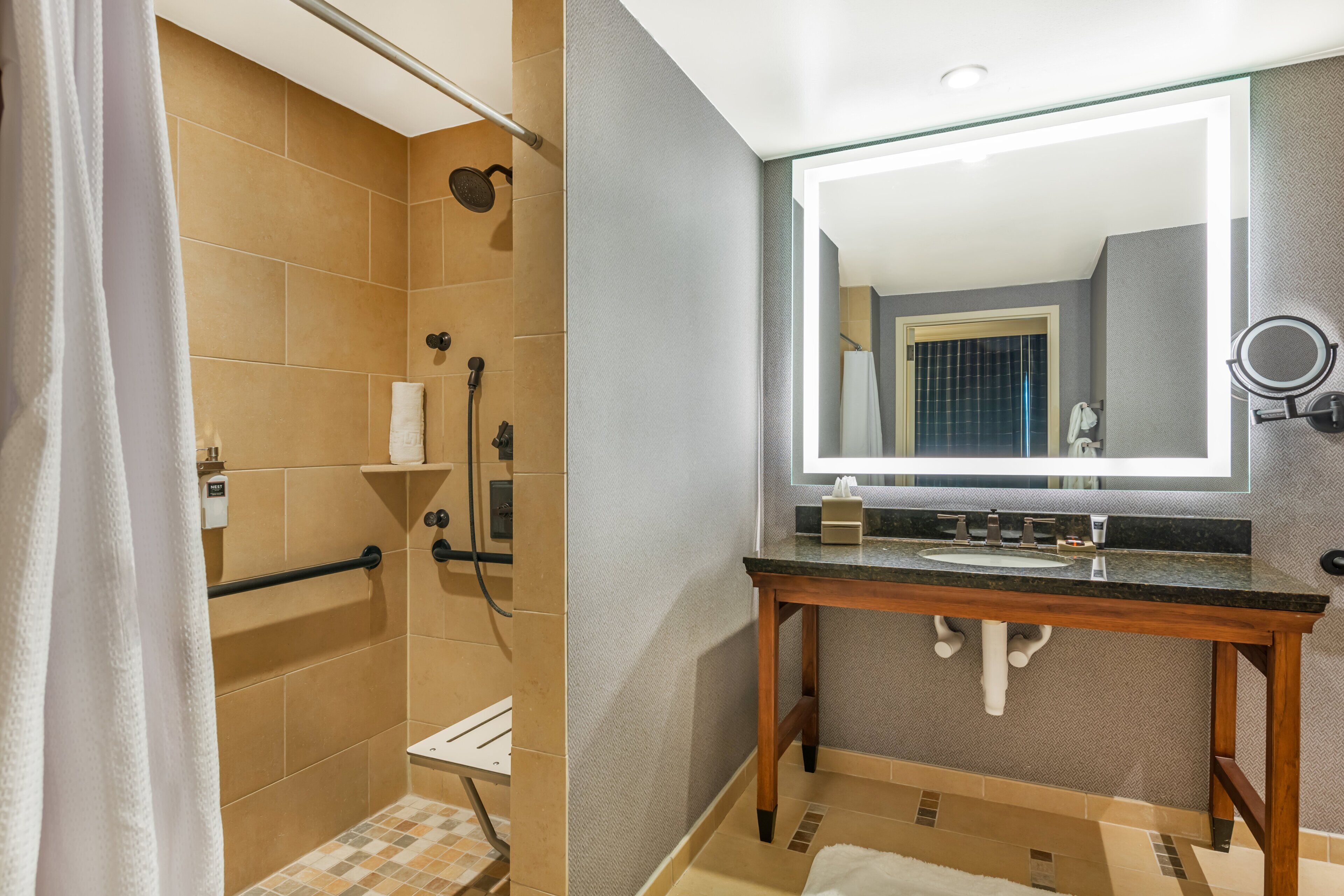 Un baño moderno con ducha, tocador con espejo y barra para toallas.