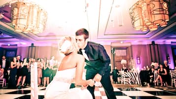 A couple dancing on a checkered floor with guests seated around them.