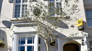 Un edificio con un cartel que dice "COURT HOTEL" y una planta grande en maceta al frente.