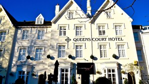 The Queens Court Hotel with a prominent sign, multiple windows, and a traditional architectural style.