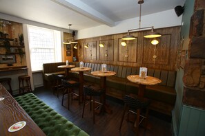 Un'accogliente zona bar con rivestimenti in legno, sedute in pelle e lampade a sospensione.
