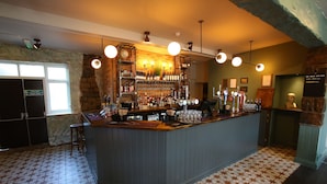 A bar area with a counter, shelves of bottles, and a variety of glasses.