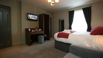 A hotel room with a bed, a desk, a television, and a wardrobe.