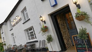 A white building with a sign reading "Rams Head Inn" and outdoor seating.