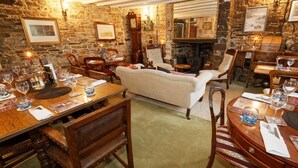 A cozy room with a fireplace, wooden furniture, and stone walls.