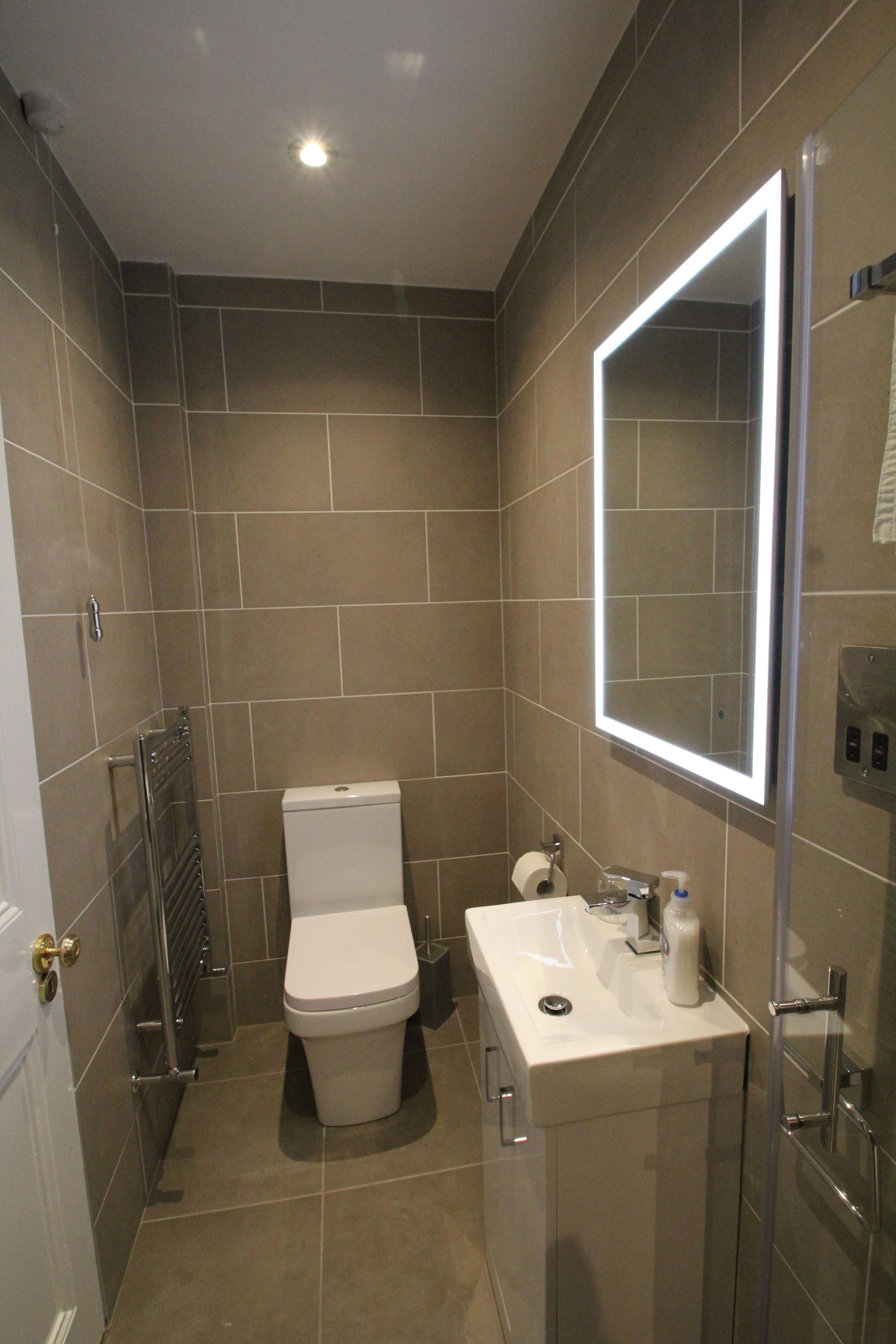 A modern bathroom with a toilet, sink, and mirror.
