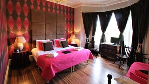 Une chambre d’hôtel avec un grand lit, deux tables de chevet, une commode, une chaise et un téléviseur.