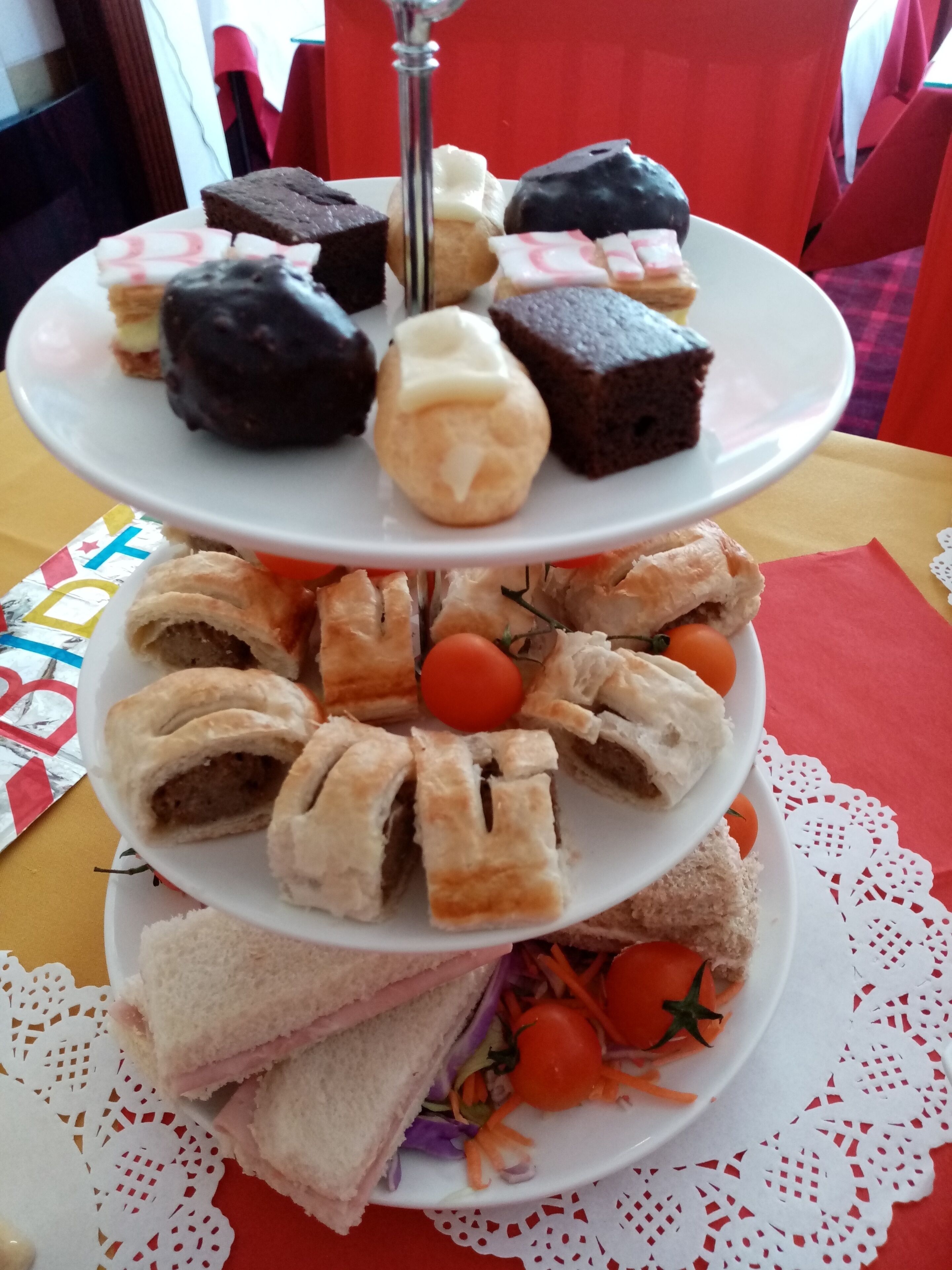 Eine mehrstöckige Dessertplatte mit verschiedenen Gebäcken und Sandwiches.