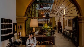 Un espace intérieur comprenant un coin repas avec une table et des chaises, une lampe décorative et une grande porte en arc donnant sur une autre pièce.