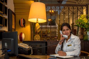 Ein Hotel-Rezeptionsschalter mit Telefon, Computer und einer Schreibtischlampe.