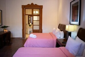 A hotel room with two beds, a wooden door, a bedside table with a lamp, and a framed picture on the wall. - Casa Aspeytia Hotel Boutique (Querétaro)