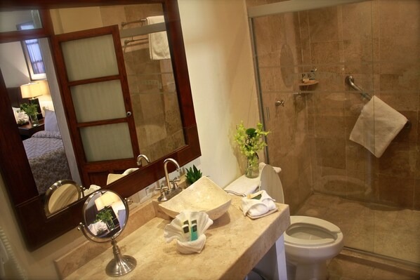 Un baño con un espejo grande, lavamanos e inodoro.