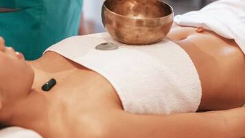 A person receiving a massage with a metal bowl placed on their back.