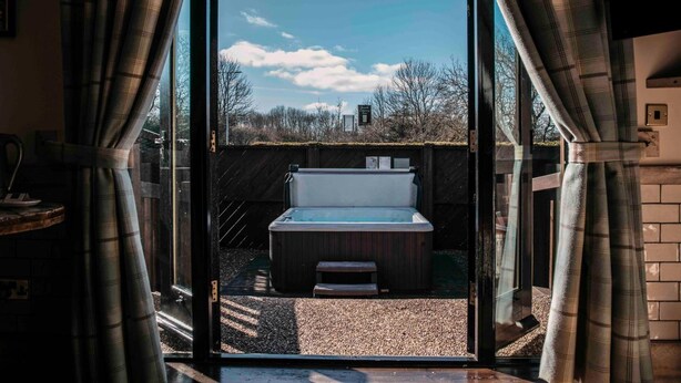 A modern bathroom with a glass door, a hot tub, and a view of the surrounding area. - South Causey Inn (Stanley)