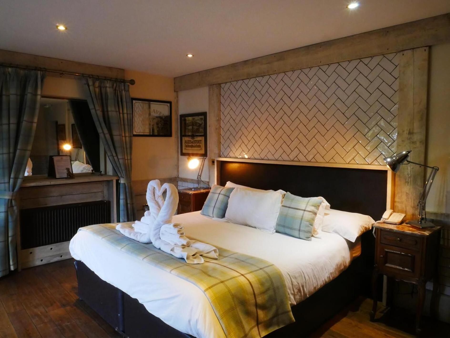 A hotel room with a large bed, a wooden headboard, a nightstand with a lamp, and a mirror.