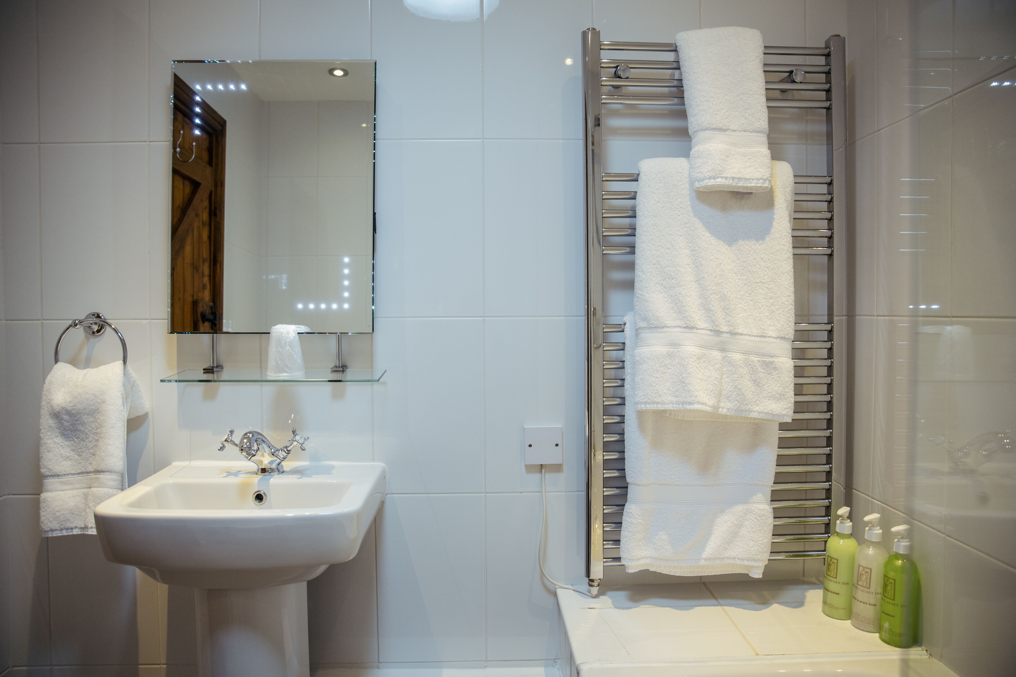 Une salle de bain équipée d’un lavabo, d’un miroir, d’un porte-serviettes et d’articles de toilette.