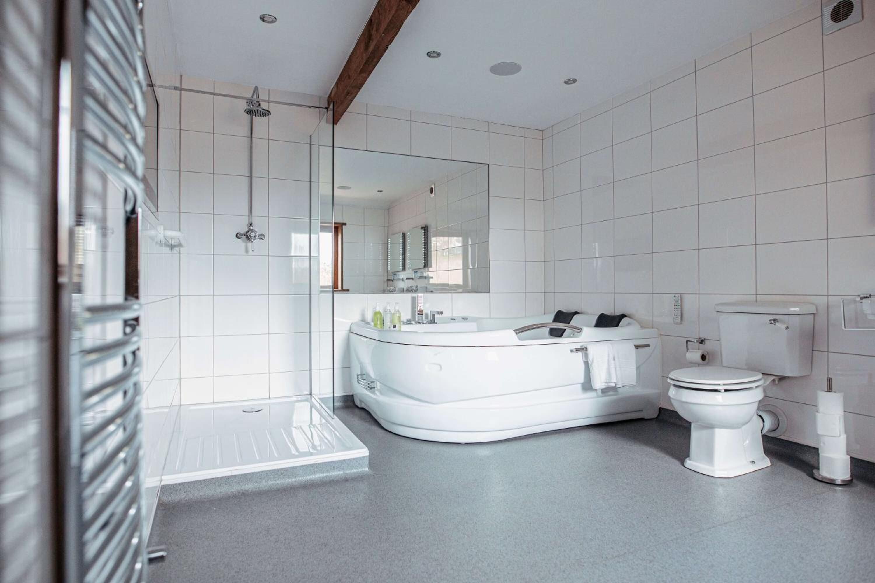 A modern bathroom with a freestanding bathtub, a separate toilet, and a glass-enclosed shower area.