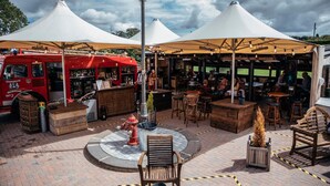 An outdoor seating area with tables and chairs, a fire hydrant, and a red food truck. - South Causey Inn (Stanley)