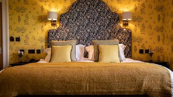 A double bed with a floral headboard, two bedside lamps, and a patterned wall.