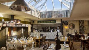 A restaurant with a high ceiling and skylight, wooden tables and chairs, a bar area, and a rustic decor. - South Causey Inn (Stanley)
