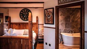 A room with a wooden bed, a large wall clock, a framed sign reading "Ladies", and a bathtub. - South Causey Inn (Stanley)