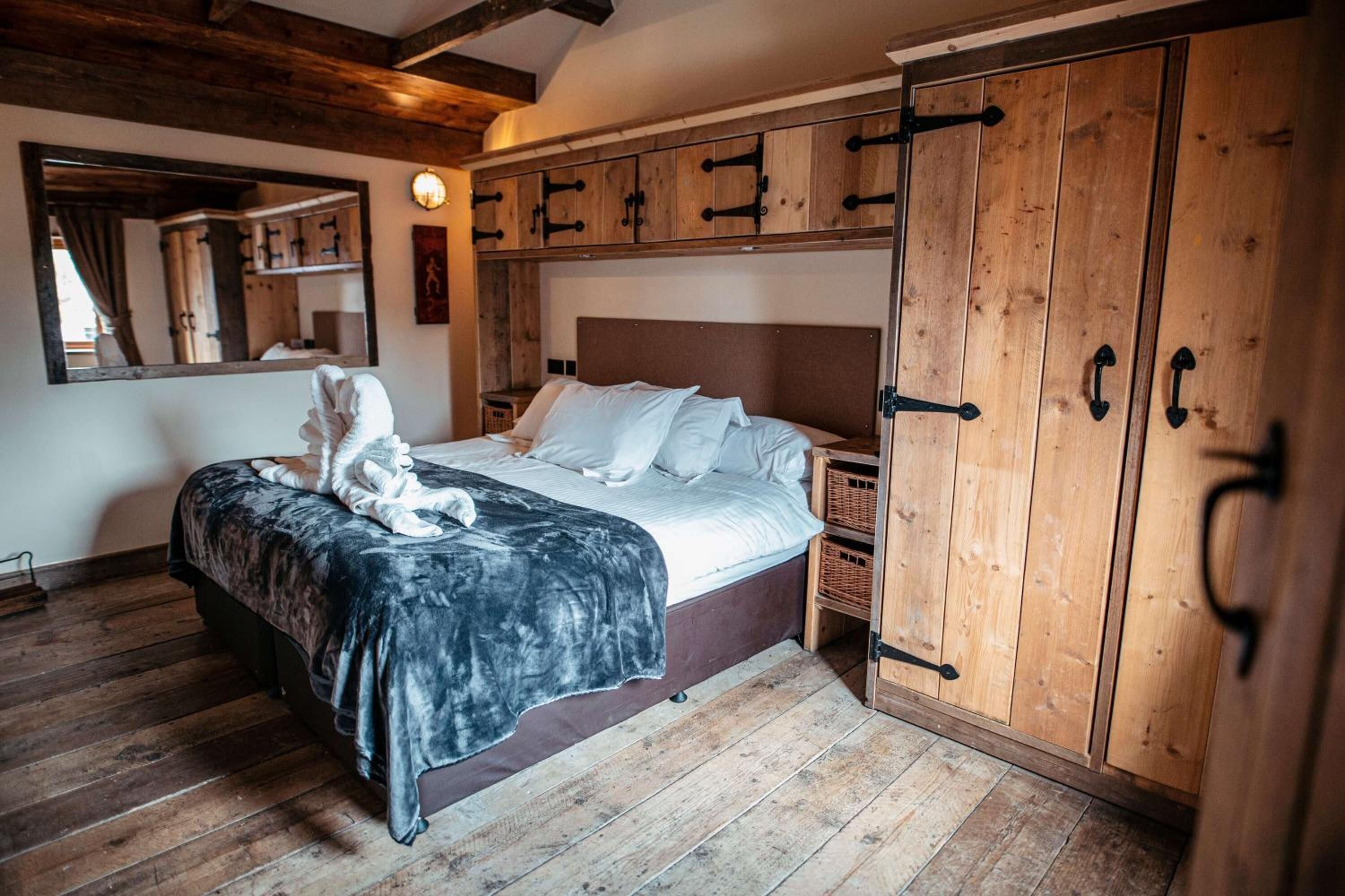 A bedroom with a wooden bed, a large mirror, and wooden wardrobes.