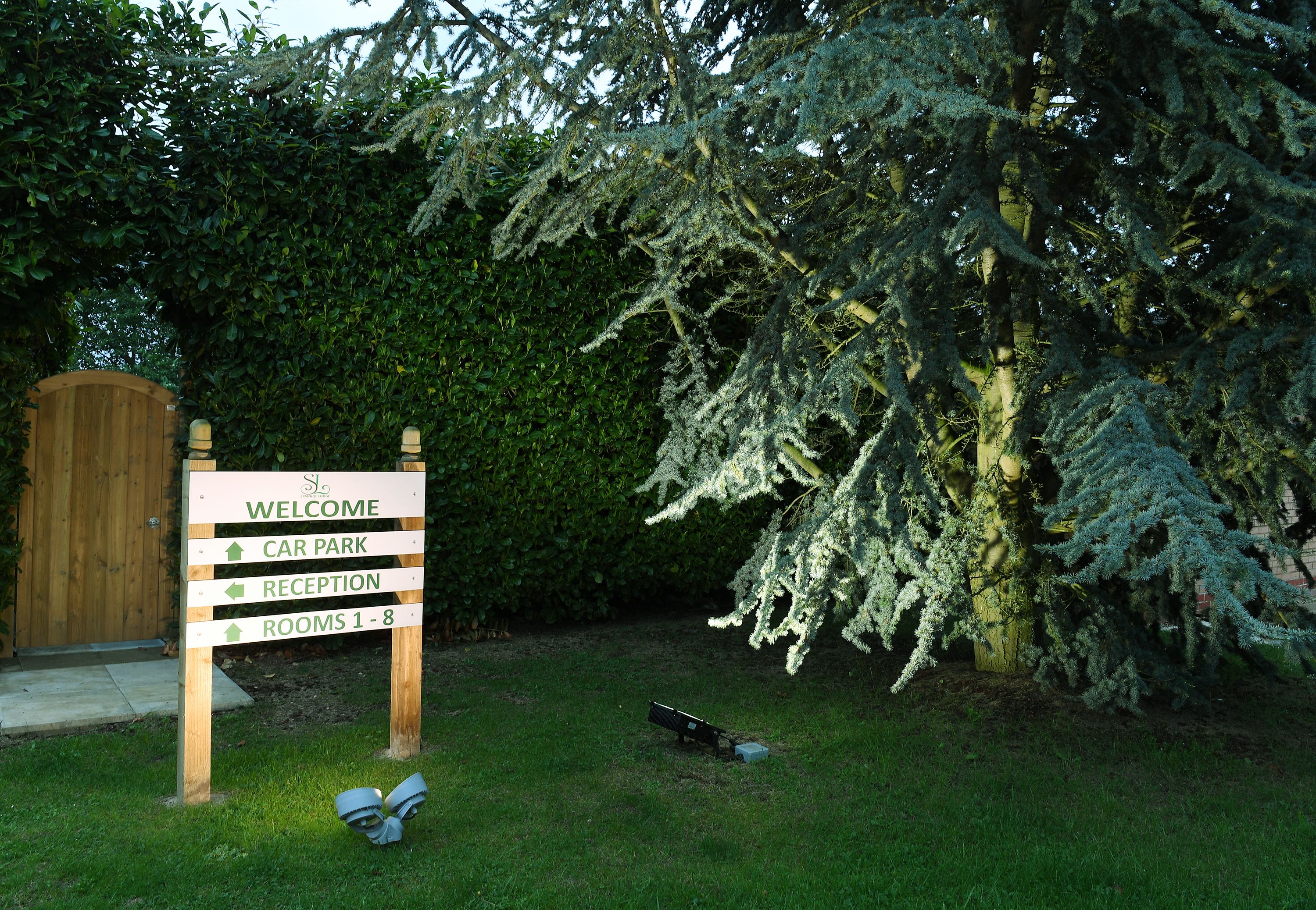 A welcome sign with directions to car park, reception, and rooms 1-8.