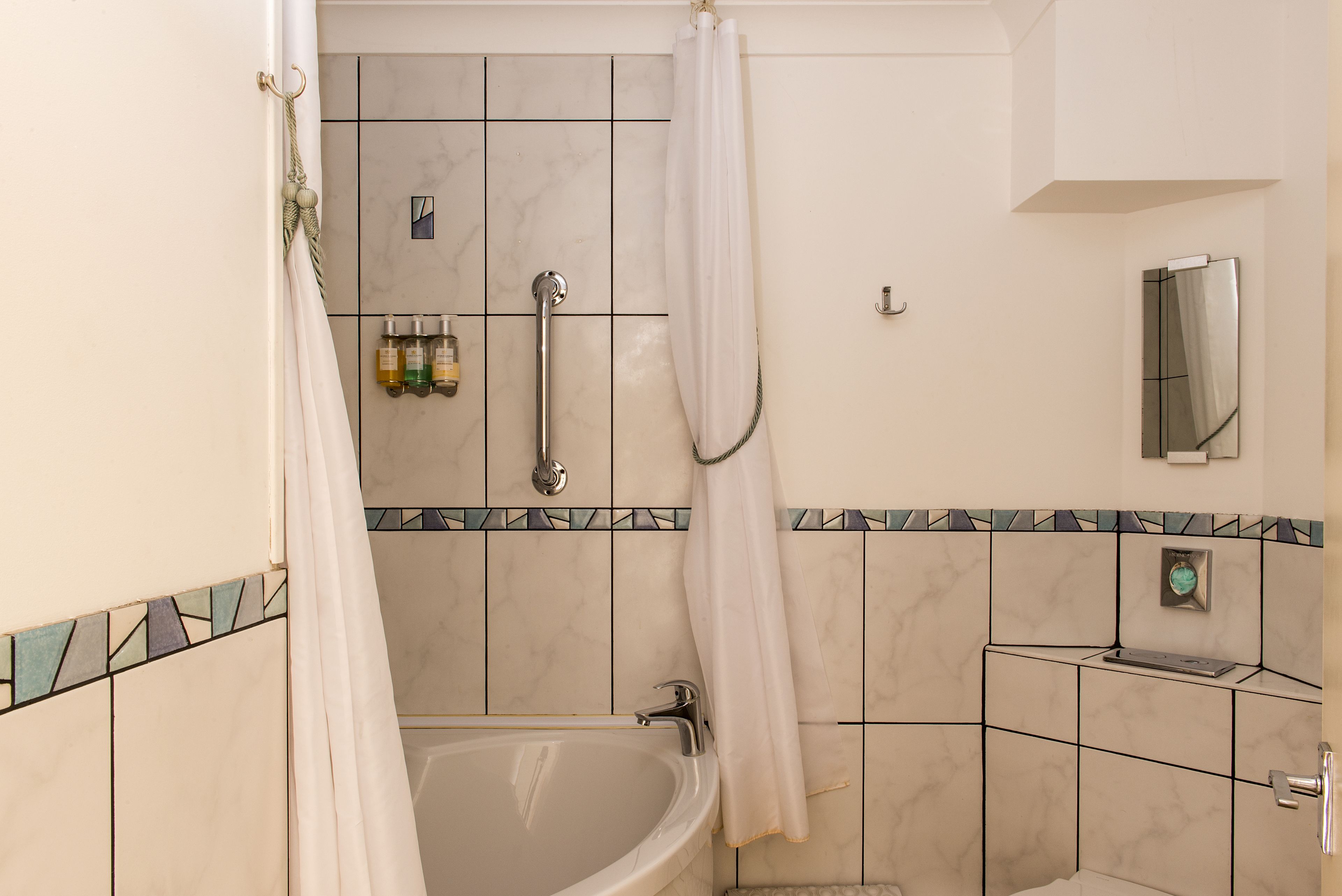 Ein Badezimmer mit Badewanne, Dusche und Toilette. An der Wand befinden sich Pflegeprodukte und ein Handtuchhalter.