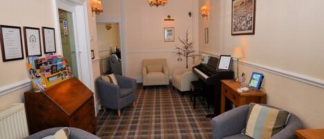 Una sala de estar acogedora con piso a cuadros, un piano y dos sillones.