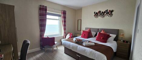 A bedroom with a bed, bedside table, lamp, and a window with curtains.