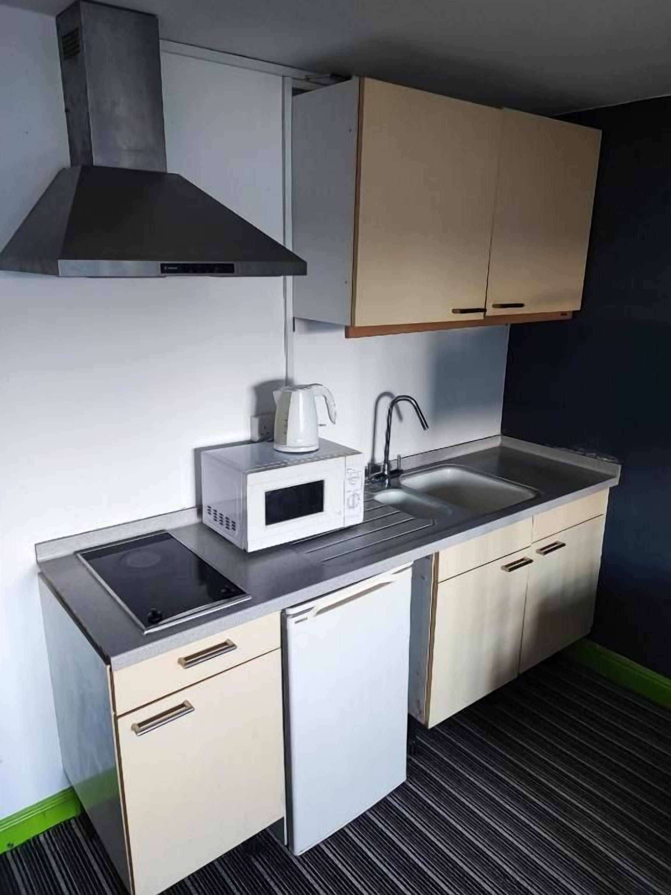 Cocina compacta con microondas, hervidor, lavabo y lavavajillas pequeño.
