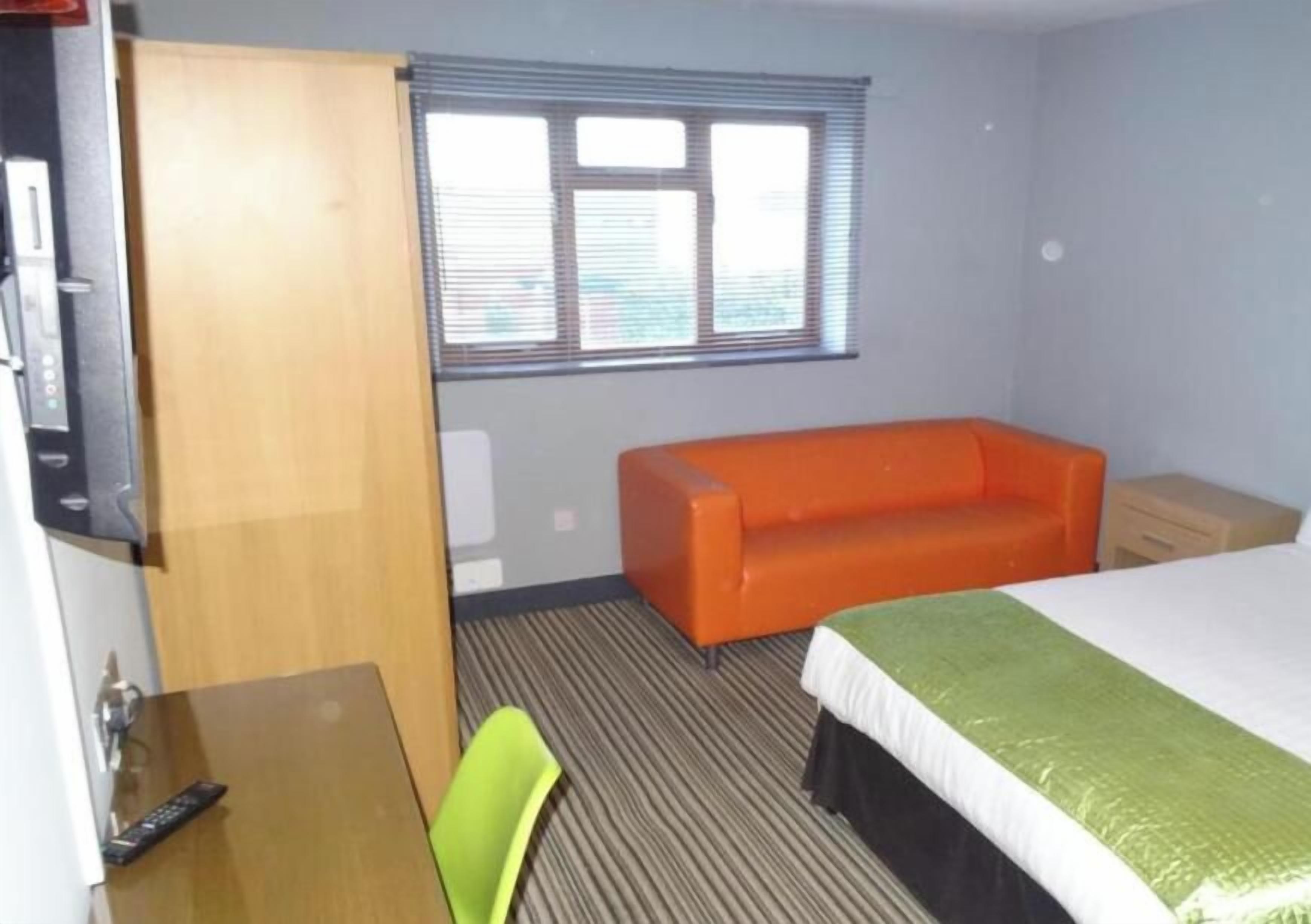 A hotel room with a bed, a sofa, a desk, and a window.