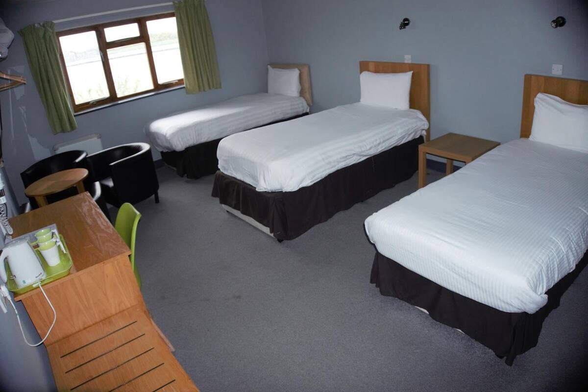 A hotel room with two single beds, a desk with a chair, and a small table.