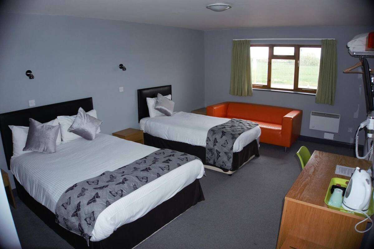 A hotel room with two beds, a desk, and a window with curtains.