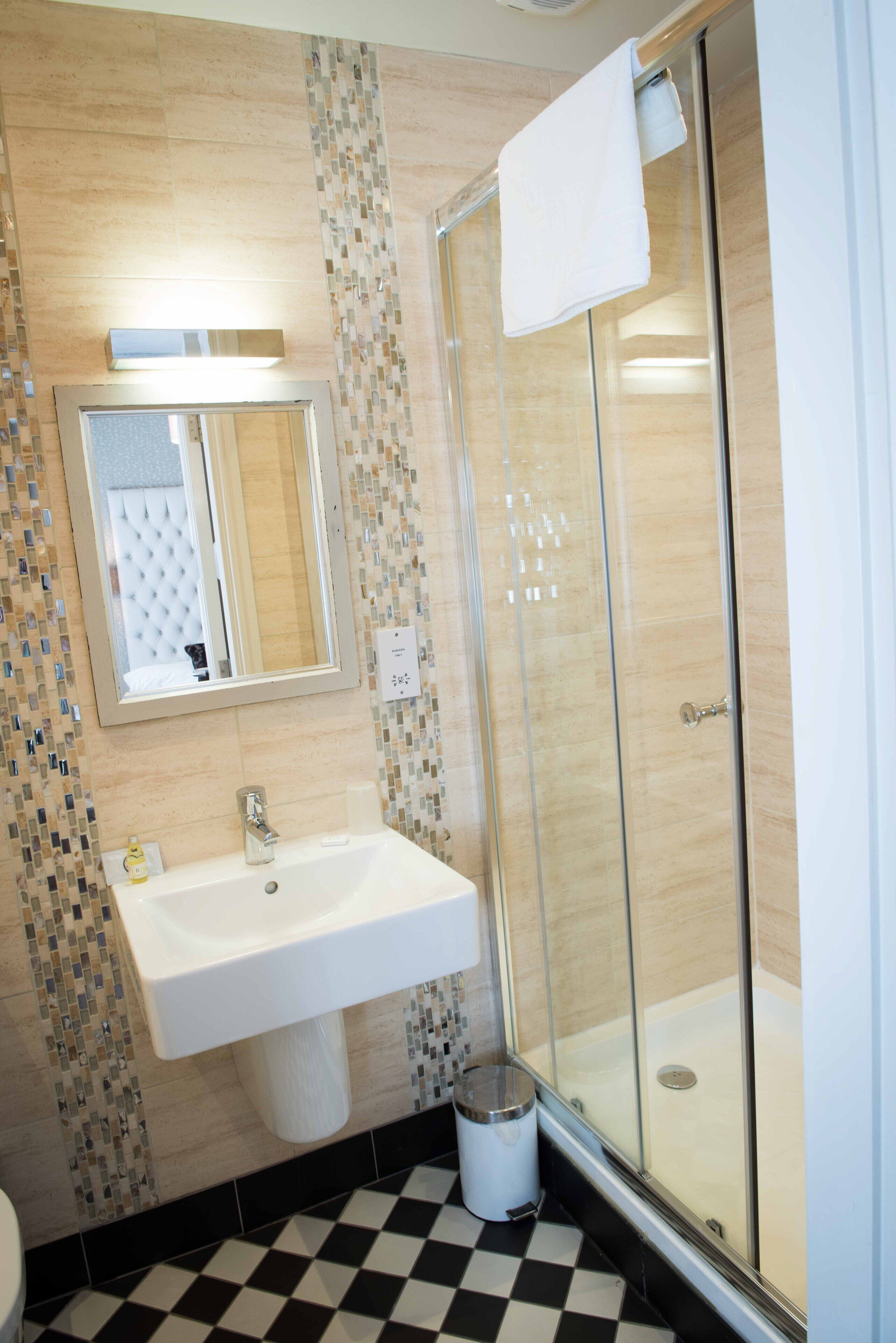 Un baño con ducha de vidrio, lavamanos y espejo.
