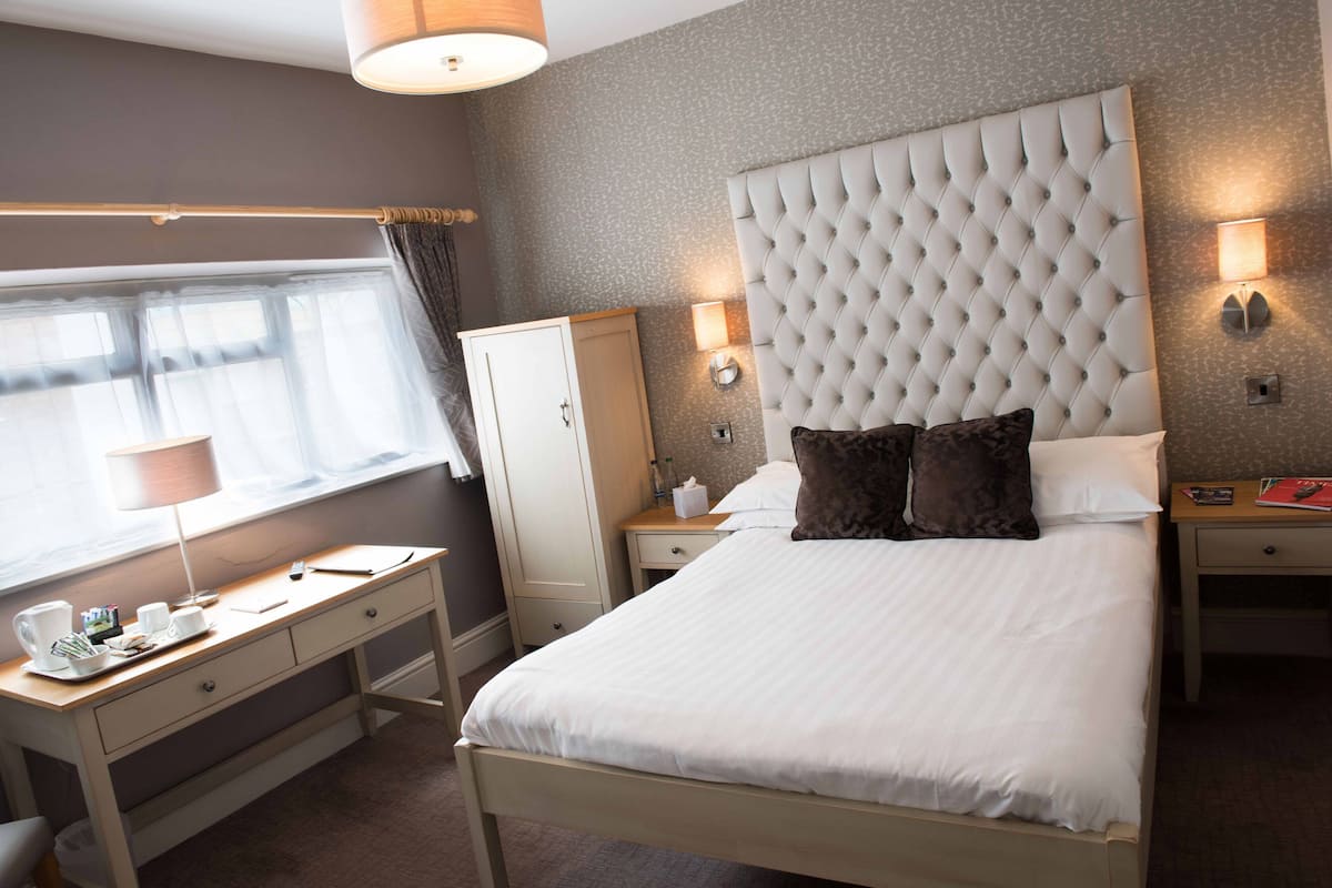 Una habitación de hotel ordenada con una cama grande, un escritorio y un armario.