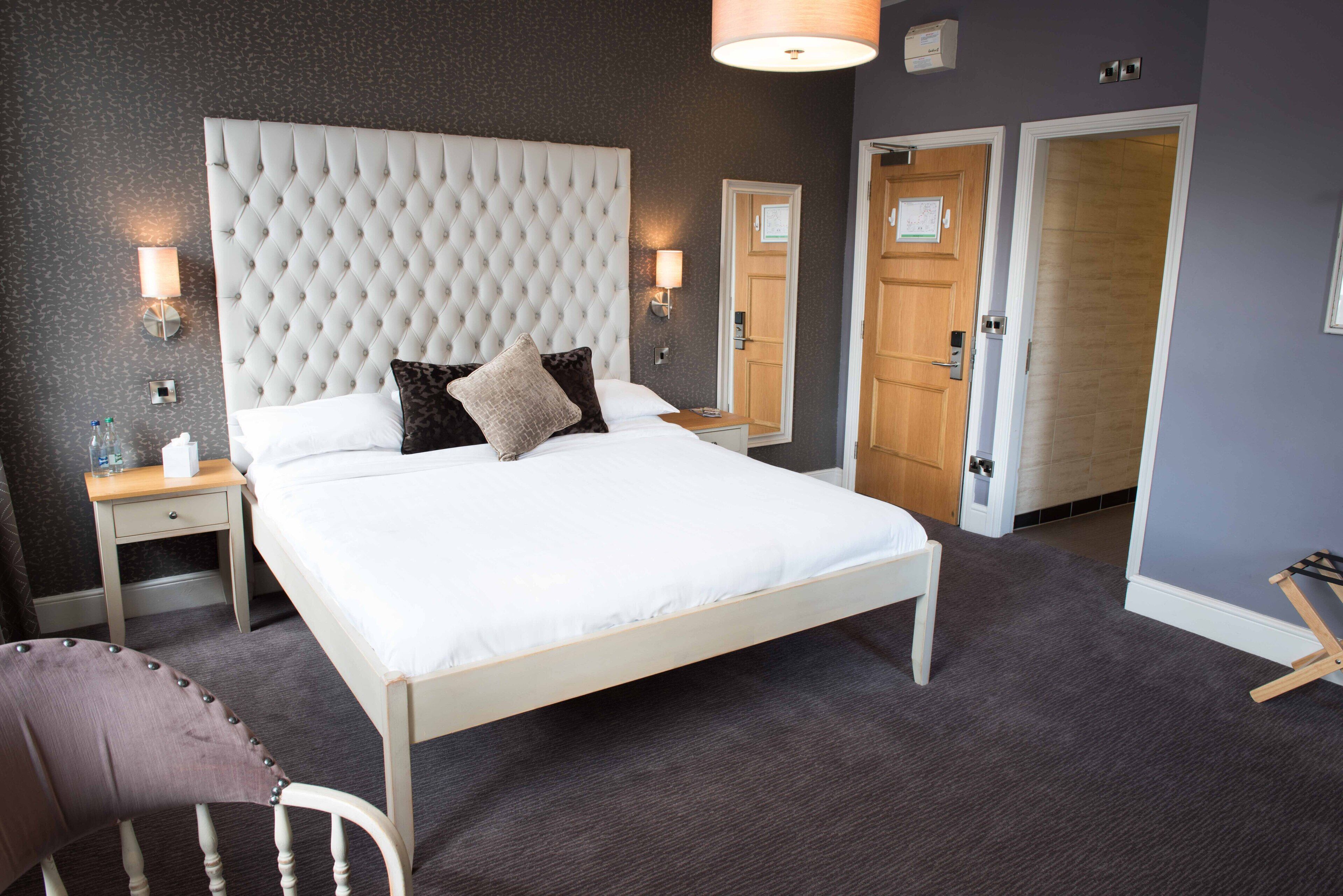 A neatly arranged bedroom with a large bed, bedside tables, and a chair.